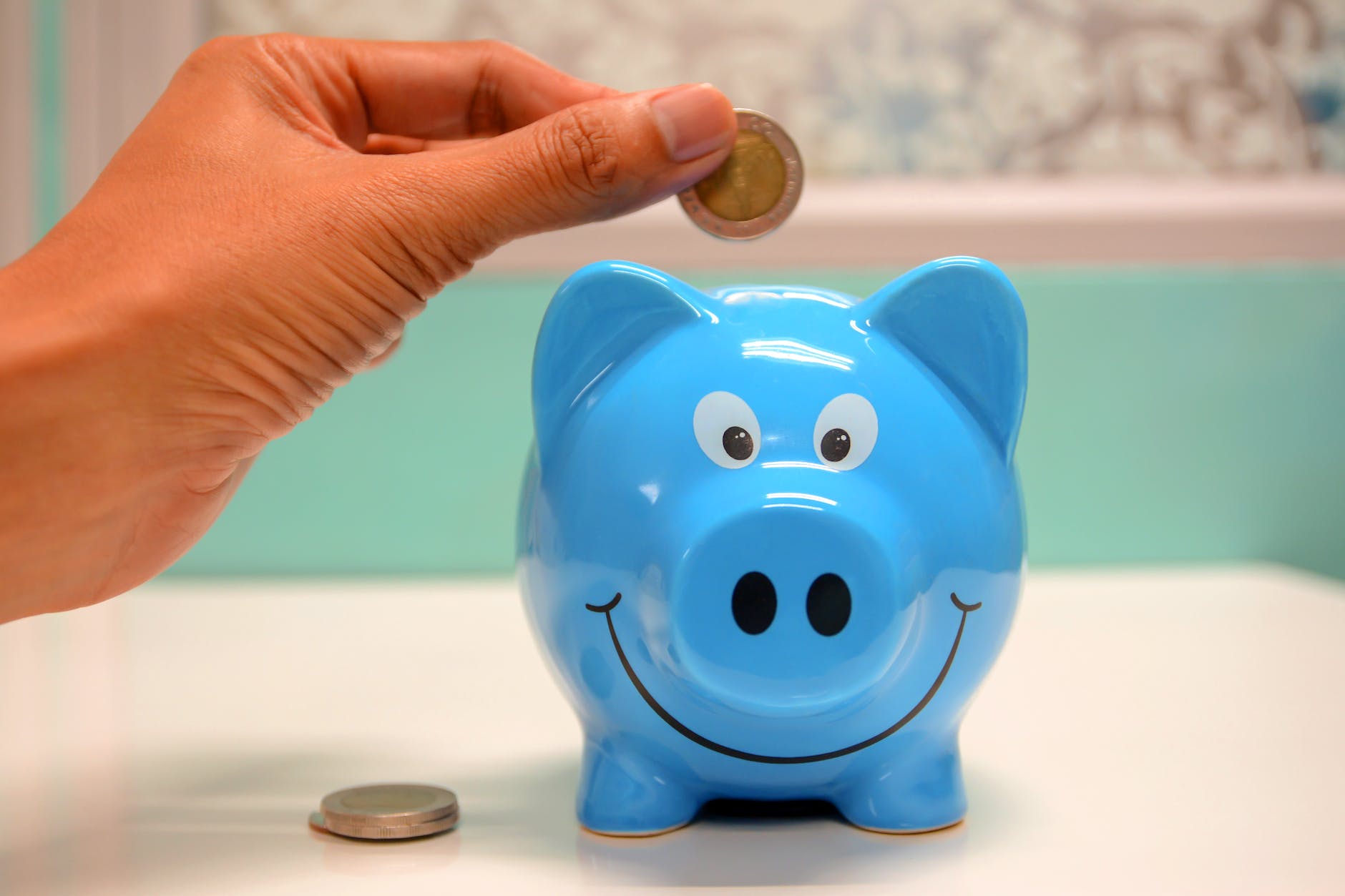 person putting coin in a piggy bank financial goals